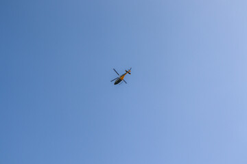 Fototapeta na wymiar Helicopter Flying Through The Sky Over Mountains