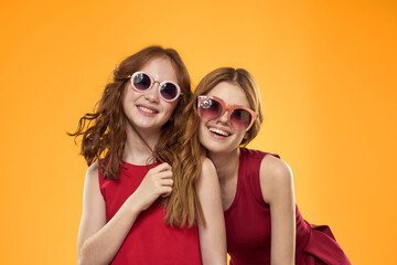 Happy woman and little girl in red dress are having fun on a yellow background fashion emotions sisters fun Copy Space.