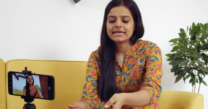 Young woman recording video of herself at home for social media vlog influencer product meeting video call via smart mobile device live product latest camera review analysis critic tech to followers 