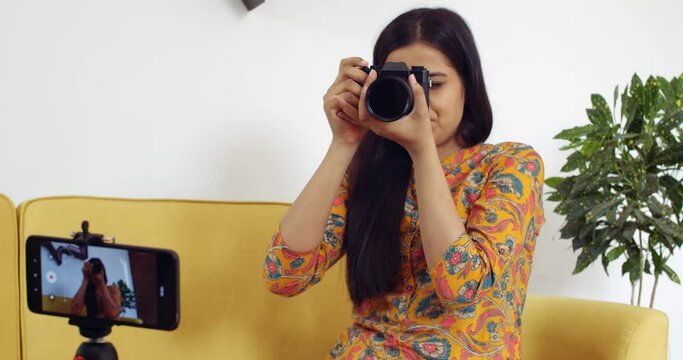 Young woman recording video of herself at home for social media vlog influencer product meeting video call via smart mobile device live product latest camera review analysis critic tech to followers 