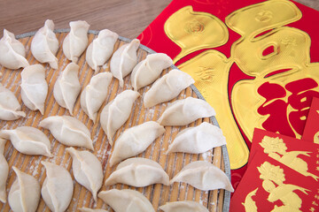 Wrapped white noodle dumplings and golden spring couplets and festive red envelopes