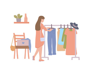 Woman at fashion thrift shop choosing second hand clothes from rack.