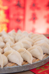 Fototapeta na wymiar Wrapped white flour dumplings on a tray in front of a red background