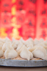 Fototapeta na wymiar Wrapped white flour dumplings on a tray in front of a red background