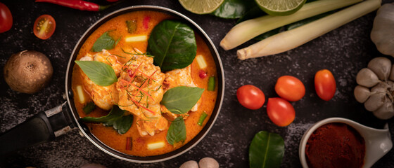 Chicken curry in a pan with lemongrass, kaffir lime leaves, tomatoes, lemon, and garlic