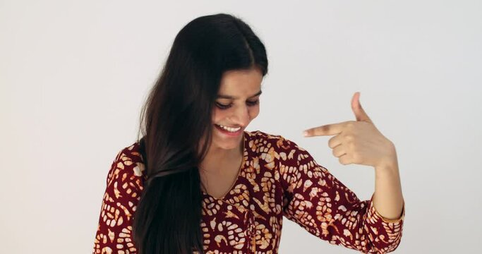 Asian female with black hair points a finger at herself in shock and pleasantly surprised at the result wins victory someone calls her draws attention disbelief good news taken aback smiling concerned