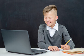 Young boy uses laptop at school