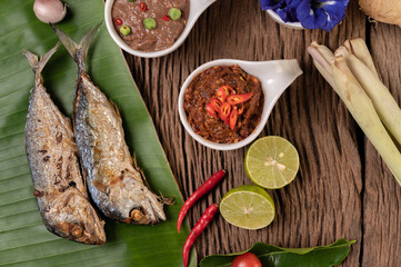 Shrimp paste, mackerel, fried on banana leaves, chili, tomato, garlic and lemon on wooden floor.
