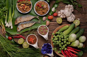 Shrimp paste, mackerel, fried on banana leaves, chili, tomato, garlic and lemon on wooden floor.