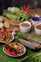 Shrimp paste, mackerel, fried on banana leaves, chili, tomato, garlic and lemon on wooden floor.