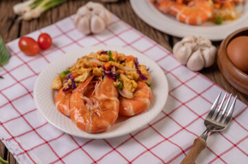 Fried shrimp with eggs in a white plate placed on a cloth with a fork.
