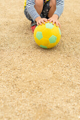 Naklejka premium 黄色いサッカーボールを持つ幼児