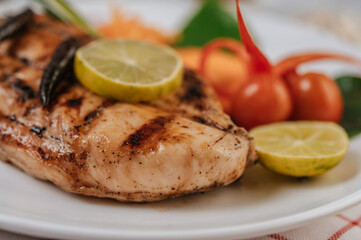 Chicken Steak with Lemon, Tomato, Chili, and Carrot on White Plate.