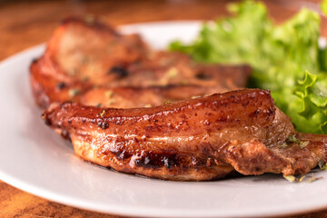 Homemade pork chop served with lettuce on a white plate.