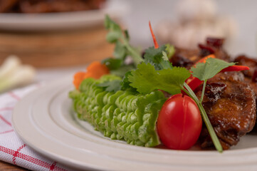 Sweet pork in a white plate with chopped scallions, chili, lime, gourd, tomato and garlic.