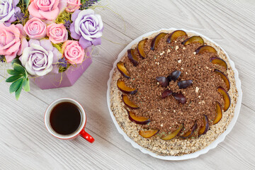 Chocolate cake decorated with plums and cup of coffee