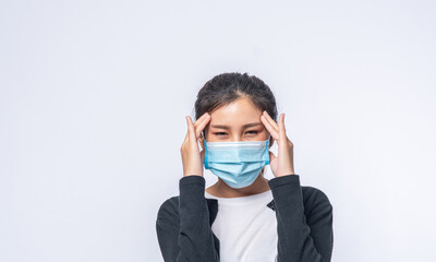 A sick woman with a headache wore a mask and placed a hand on her head.