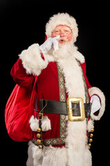 Happy excited Santa Claus portrait with a big gift bag on his shoulder, ready to deliver the gifts; isolated on black background 