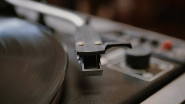 hands repeatedly put down a vintage turntable stylus jumping off a spinning vinyl record