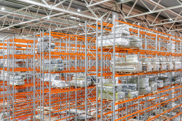 Large warehouse. Tall and long metal racks filled with various boxes, containers and drawers
