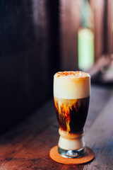 Iced coffee cappuccino   with cream poured over in a tall glass on wooden table