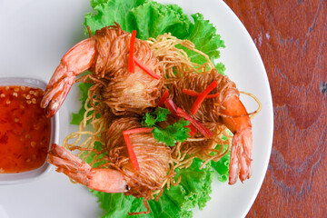 Goong Sarong  noodles Wrapped Shrimp With Crispy Noodle Serve, vegetable and sauce in white plate  on wood table , Thai food