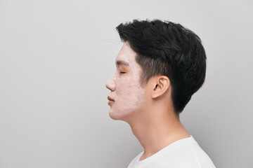 Handsome man with clay mask on his face against color background