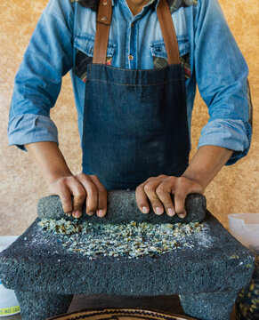 chef grinding corn in stone metate, traditional method to make tortillas, artisan method of grinding corn