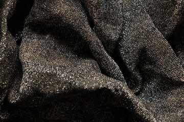 black shiny crumpled shawl as background close up