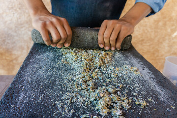 chef grinding corn in stone metate, traditional method to make tortillas, artisan method of grinding corn - obrazy, fototapety, plakaty