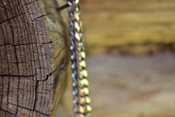 section of a log close-up with a blurred photo of a chain made of jewelry steel