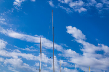 Masts of sailing ships yacht on blue sky background in marina.
