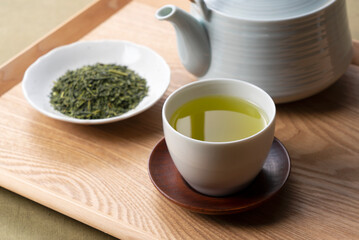 Green tea and tea leaves on a wooden tray