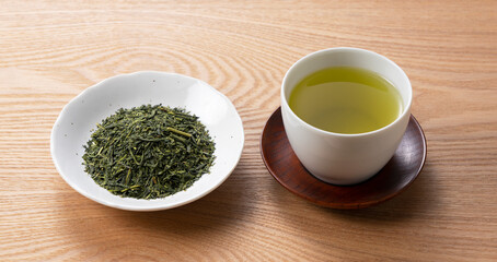Green tea and tea leaves on a wooden tray