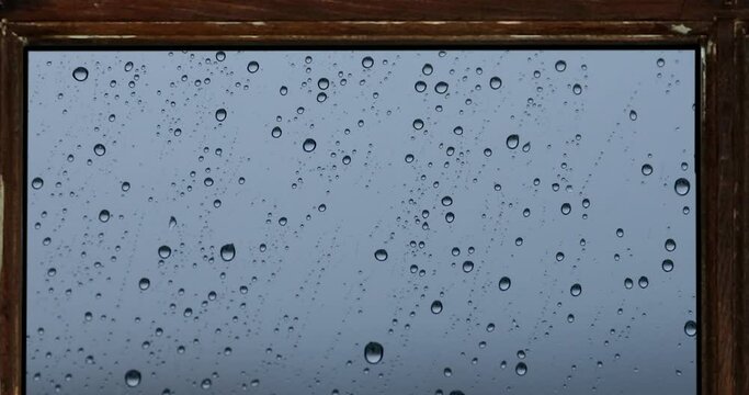 Raindrops filtering through the misty glass. The raindrops falling in front of the window in the autumn fall from the window.