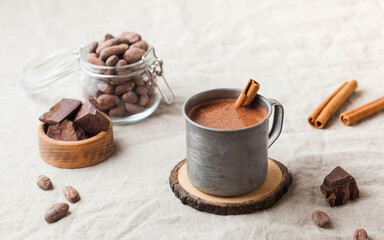 Hot chocolate in a metal mug with a cinnamon stick on the tablecloth. Copy space