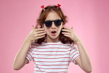 Cheerful girl with pigtails sunglasses striped t-shirt lifestyle pink background