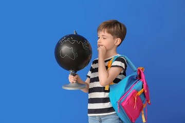 Little schoolboy with globe on color background