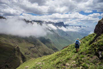 Fototapeta na wymiar A hiker on a trail/ path high in the Drakensberg mountains with the spectacular range stretching away in the distance.