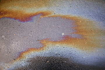 Color gasoline fuel spot on black asphalt, industrial pollution concept.