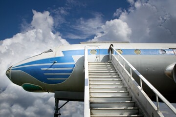 Stairs and entrance to a transport aircraft parked in the open air.Airliner under blue sky with clouds. To the skies and clouds.