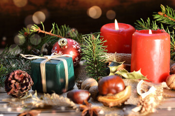 traditional christmas decoration on wooden background with candles and gifts in blur