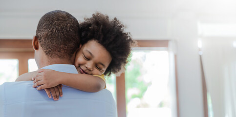 Portrait of american african father and son hugging laughing in living room. Happy daddy and his...