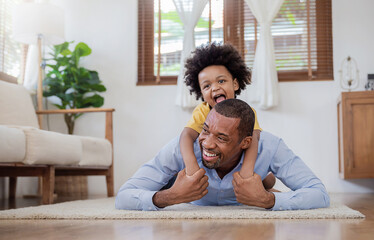 Portrait of american african father and son kissing laughing and bonding on living room floor. Daddy and his little boy spending leisure time at home. Single dad, family lifestyle father's day concept