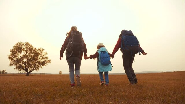 happy family tourists run in the park with backpacks. teamwork. adventure travel activities a concept. happy family hackers run holding hands. tourists run in the wild park outdoor
