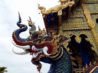 Fototapeta na wymiar Chiang Rai. Thailand, June 16, 2017: Wat Rong Suea Ten. Dragon head on the stairs of the Blue Temple in Chiang Rai, Thailand