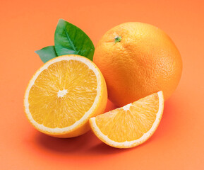 Orange fruit with orange slices and leaves isolated on orange background.