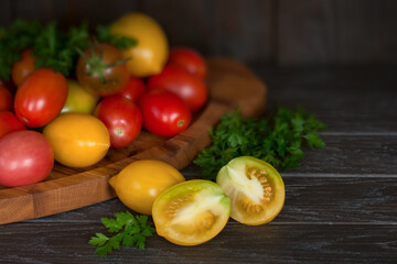 fresh tomatoes and sprigs of parsley on the table close-up. background with red and yellow tomatoes in a wooden box.