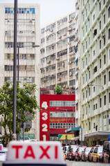 Taxi transportation in Hong Kong with typical urban decay residential and office buildings and busy...