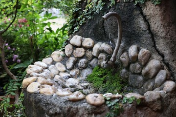 The faucet and sink are made of natural stone in vintage style in the outdoor garden.